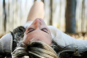 Beautiful blonde girl lying on leaves in a forest of poplars photo