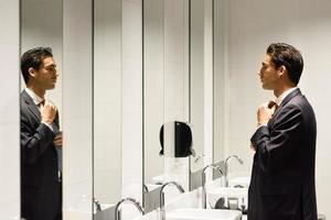 Man getting dressed in a public restroom with mirror photo