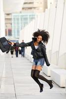 Young pretty black woman jumping in the street with a briefcase photo