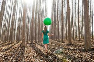 Beautiful blonde girl, dressed in green, walking into the forest photo