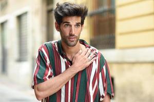 joven atractivo con cabello oscuro y peinado moderno con ropa informal al aire libre foto