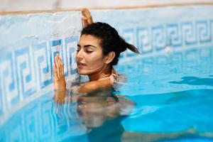 Beautiful Arab woman relaxing in swimming pool. photo