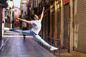 Young black man doing an acrobatic jump in the middle of the street. photo