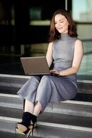 mujer de negocios usando su computadora portátil en un edificio de oficinas moderno foto
