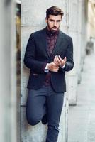 Young bearded man in urban background wearing british elegant suit in the street. photo