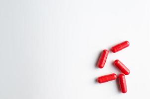 Red capsule pills on white background photo