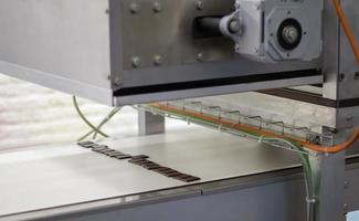 Production of sweets in a chocolate factory. Food industry plant. A male worker in uniform oversees the production process of an automated conveyor belt. Master factory worker. photo