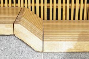Empty modern wooden benches without people on a sunny day, public places in the city park. City improvement, urban planning, public spaces, recreation area. City public anti-vandal furniture for rest. photo