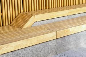 Empty modern wooden benches without people on a sunny day, public places in the city park. City improvement, urban planning, public spaces, recreation area. City public anti-vandal furniture for rest. photo