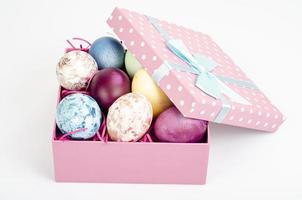 Multicolored eggs in open gift box. Concept of the Happy Easter holiday, greeting card template. Studio Photo