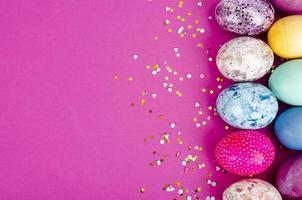 Multicolored handmade easter eggs and confetti on pink background. Minimal concept. View from above. Space for text. Studio Photo