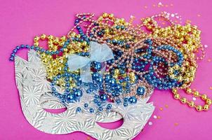 Color mardi gras beads, masks on bright background. Studio Photo