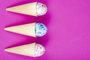 Vanilla ice cream waffle horns with decoration eggs on pink background. Minimalism. Creative Easter concept. Studio Photo