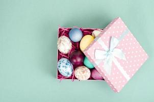 Multicolored eggs in open gift box. Concept of the Happy Easter holiday, greeting card template. Studio Photo