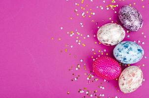 Multicolored handmade easter eggs and confetti on pink background. Minimal concept. View from above. Space for text. Studio Photo