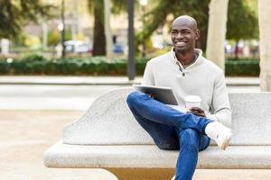 Black young man with tablet computer and take away coffee photo