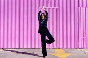 Woman wearing blue suit posing near pink shutter. photo