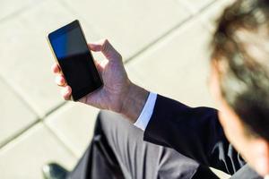 hombre de negocios usando su teléfono inteligente en la calle foto