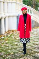 mujer de mediana edad con ropa roja de invierno caminando por un parque urbano. foto