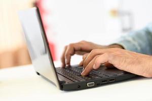 Hands of a man typing with a laptop computer photo