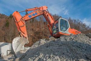 Bulldozer at work while charging trucks in gravel pit photo