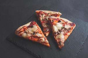 slices of freshly baked pizza on a black serving chalkboard