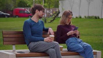 Two friends, sit on the bench while sipping coffee to-go Coffee Break work Wearing. video