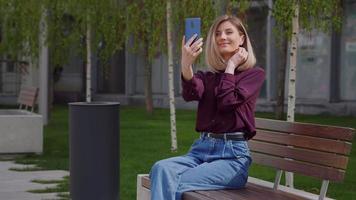 Pretty woman taking selfie photo on smartphone in park video