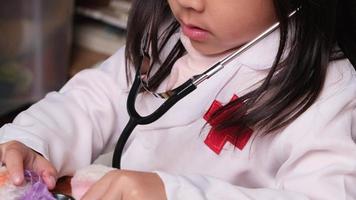 Cute young girl playing doctor with stethoscope and stuffed toys at home.