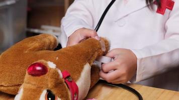 jolie jeune fille jouant au docteur avec stéthoscope et jouets en peluche à la maison. video