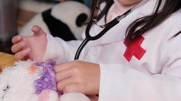 Cute young girl playing doctor with stethoscope and stuffed toys at home. video