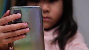 schattig klein meisje kijken naar tekenfilms op slimme telefoon thuis. video