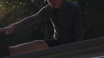 gezonde tienerjongens warmen zich op voordat ze gaan rennen. een jonge mannelijke atleet die zich uitstrekt in het park voordat hij gaat joggen. gezond levensstijlconcept video