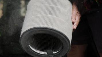 a mão de um homem segura um filtro purificador de ar sujo que contém poeira e bactérias pm 2,5 depois de usar por um longo tempo. close-up da limpeza do filtro do purificador de ar com um secador. video