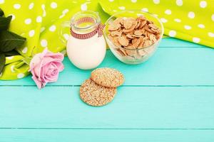 Oat flakes and cookies with jug of milk in the cafe. Tablecloth in polka dots and pink rose. selective focus photo