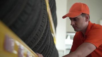 Employees or customers are viewing tires. Buy auto parts and get vehicle inspection services in auto garage, choose a new tire for car video