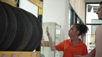 funcionários ou clientes estão vendo pneus. compre autopeças e obtenha serviços de inspeção de veículos na garagem de automóveis, escolha um novo pneu para o carro video