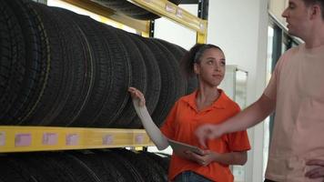 werknemers of klanten bekijken banden. koop auto-onderdelen en krijg voertuiginspectiediensten in de autogarage, kies een nieuwe autoband video