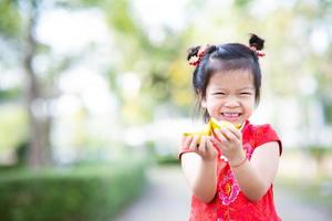 Portrait laughing kid girl was holding two gold coins. Chinese New Year greeting concept. Child wear red cheongsam. Empty space to enter text. photo