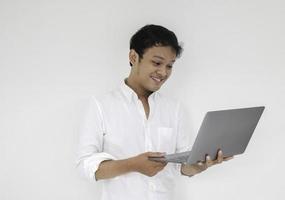 Young asian man is smile and enjoy when working at home with laptop computer. Work from home concept. photo