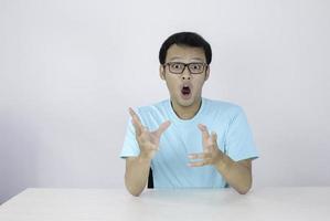 guau y cara conmocionada de un joven asiático con gesto de mano abierta. concepto de modelo publicitario con camisa azul. foto