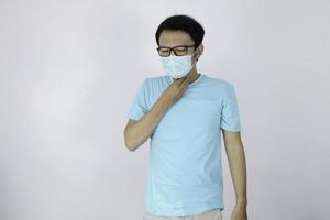 Young Asian man having sore throat and touching his neck with wearing medical mask. photo