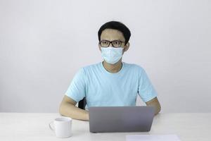 Young Asian man in blue t-shirt with serious work with the laptop on the table and looking outside photo
