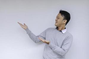 Smile of Young Asian man in white shirt with hand point on empty space photo