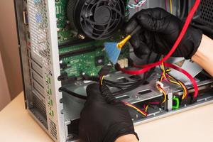 Wizard repairs personal computer with tools and hands. Disassembly of the computer into spare parts photo