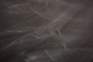 Dark gray background with white blurry waves. Smoke abstraction. photo