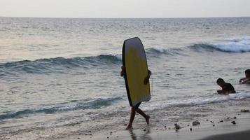 documentación de surfistas en acción al atardecer con un color dorado y oscuro, desenfocado y oscuro en la playa de senggigi lombok, oeste de nusa tenggara indonesia, 27 de noviembre de 2019 foto