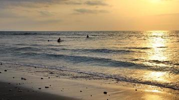 Documentation of surfers in action at dusk with a golden color and dark, unfocused and dark on the beach of Senggigi Lombok, West Nusa Tenggara Indonesia, 27 November 2019 photo