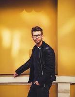 young man standing against yellow background photo