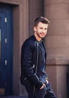 man in leather jacket posing in city photo